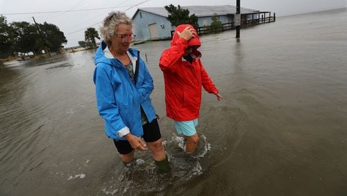 St. Marys residents Jen Fabrick (left) and Anne Herring (right) walk through flood waters covering a street near their homes as Hurricane Dorian passes near Georgia’s coast on Wednesday afternoon.   Curtis Compton/ccompton@ajc.com