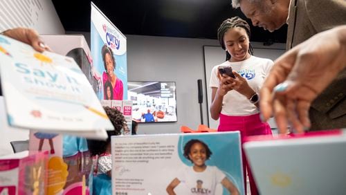 Zoe Oli, the 11-year-old CEO of Beautiful Curly Me, completes a purchase for Eddie Bradford, Herman Russell’s former CEO, during a small business market at the Russell Innovation Center for Entrepreneurs in Atlanta on Tuesday, Nov. 21, 2023. Photo by Ben Gray ben@bengray.com