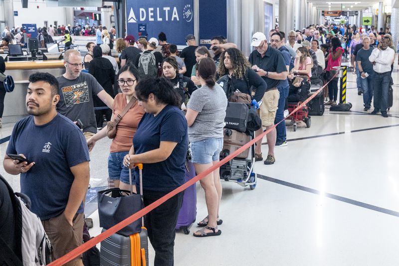 Travelers wait in a long ticket counter line Saturday at Hartsfield-Jackson Atlanta International Airport after hundreds of airline flights were canceled due to a global technology outage Friday.   (Steve Schaefer / AJC)