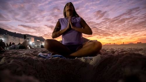 A woman sits in lotus prayer pose during the "Yoga at the Sunrise" event on Copacabana beach, in Rio de Janeiro, Saturday, June 22, 2024. The activity celebrates International Yoga Day proclaimed by the United Nations as June 21. (AP Photo/Bruna Prado)