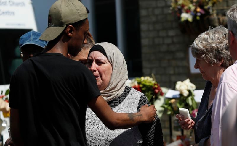 FILE - A woman is comforted after respecting a minute's silence near to Grenfell Tower in west London Monday, June 19, 2017. (AP Photo/Kirsty Wigglesworth, File)