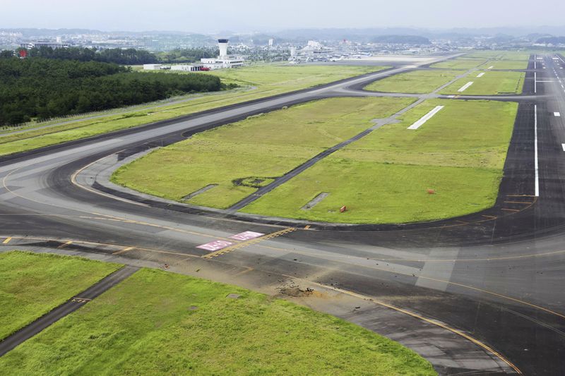 This photo taken from a Kyodo News helicopter shows part of a damaged taxiway, front, at Miyazaki Airport in southwestern Japan, Wednesday, Oct. 2, 2024, after an explosion was reported. (Kyodo News via AP)