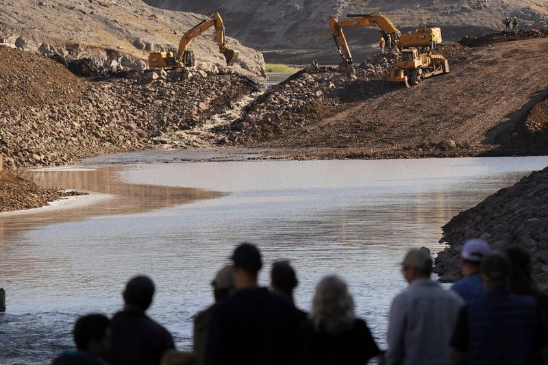 In this image provided by Matthew John Mais, people watch crews working at the Iron Gate cofferdam site along the Klamath River on Wednesday, Aug. 28, 2024, in Siskiyou County, Calif. (Matthew John Mais via AP)