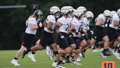 Atlanta Falcons offensive tackle Jake Matthews (70) and the rest of the offensive linemen run during an NFL training camp football practice Thursday, July 25, 2024, in Flowery Branch, Ga. (AP Photo/John Bazemore)
