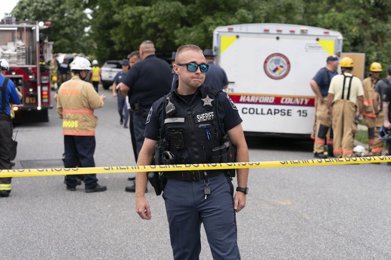 A police officer stands near a police line where a house exploded in Bel Air, Md. neighborhood on Sunday, Aug. 11, 2024. (AP Photo/Jose Luis Magana)