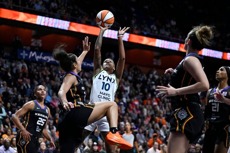 Minnesota Lynx guard Courtney Williams (10) shoots over Connecticut Sun guard Veronica Burton during the first half of a WNBA basketball semifinal game, Friday, Oct. 4, 2024, in Uncasville, Conn. (AP Photo/Jessica Hill)