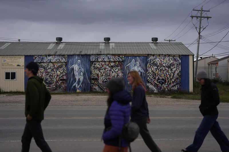 People walk near a mural on the side of a local tourism company, Monday, Aug. 5, 2024, in Churchill, Manitoba. (AP Photo/Joshua A. Bickel)