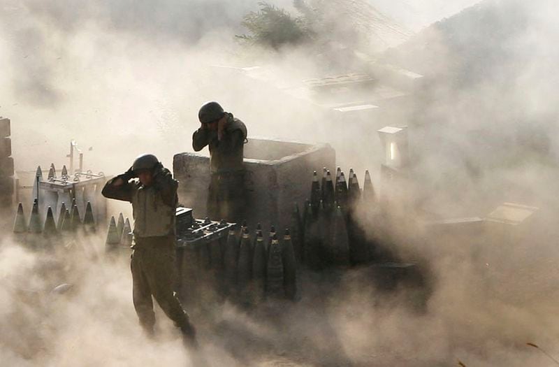 Israeli artillery soldiers are surrounded by smoke and dust as they fire across the border into southern Lebanon from a position on the frontier in Zaura, northern Israel, on July 12, 2006. (AP Photo/Oded Balilty, File)