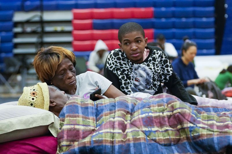 Bobby Joe Edwards, Sr., and his wife Lillie Edwards, of Walkalla, Fla., and their grandson Tavarrious Dixon, right, rest inside a hurricane evacuation shelter at Fairview Middle School, ahead of Hurricane Helene, expected to make landfall here today, in Leon County, Fla., Thursday, Sept. 26, 2024. (AP Photo/Gerald Herbert)