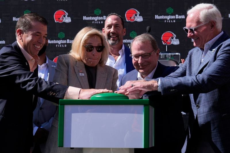 From left, Brant Standridge of Huntington Bank, Dee Haslam, Cleveland Browns owner, Steve Steinour of Huntington Bank and Jimmy Haslam, Cleveland Browns owner, press a button to display "Huntington Bank Field" on the scoreboard as they announce that Cleveland Browns Stadium will now be called Huntington Bank Field, during an NFL football news conference, Tuesday, Sept. 3, 2024, in Cleveland. At rear is David Jenkins, Browns' chief operating officer. (AP Photo/Sue Ogrocki)