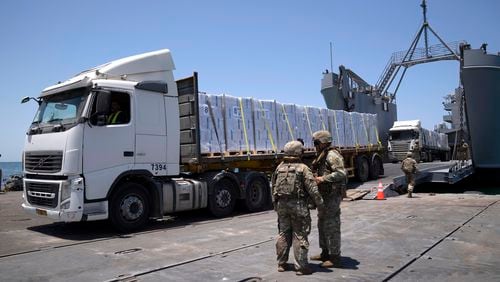 FILE - U.S. Army soldiers stand next to trucks arriving loaded with humanitarian aid at the U.S.-built floating pier Trident before reaching the beach on the coast of the Gaza Strip, June 25, 2024. (AP Photo/Leo Correa, File)