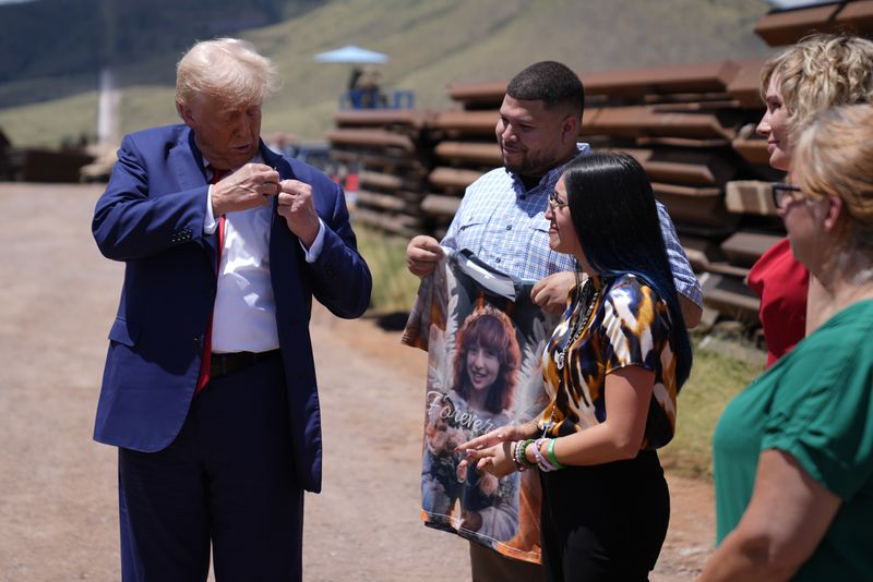 Republican presidential nominee former President Donald Trump puts a pin on his suit with a photo of Jocelyn Nungaray, given to him by her mother, Alexis, center right, as he tours the southern border with Mexico, Thursday, Aug. 22, 2024, in Sierra Vista, Ariz. (AP Photo/Evan Vucci)