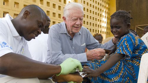 Jimmy Carter consoles a young patient having a Guinea worm removed from her body in Savelugu, Ghana, in February 2007. The Carter Center led the international campaign to try to eradicate Guinea worm disease. (Louise Gubb/The Carter Center/TNS)