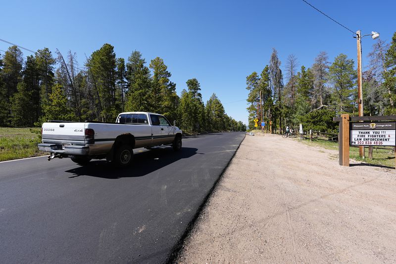 A pickup truck moves along the 23000 block of Pleasant Park Road where a teenager, who was scouting for a location for lakeside homecoming photos, was shot in the face by a town councilman earlier this week, Friday, Sept. 13, 2024, near Conifer, Colo. (AP Photo/David Zalubowski)