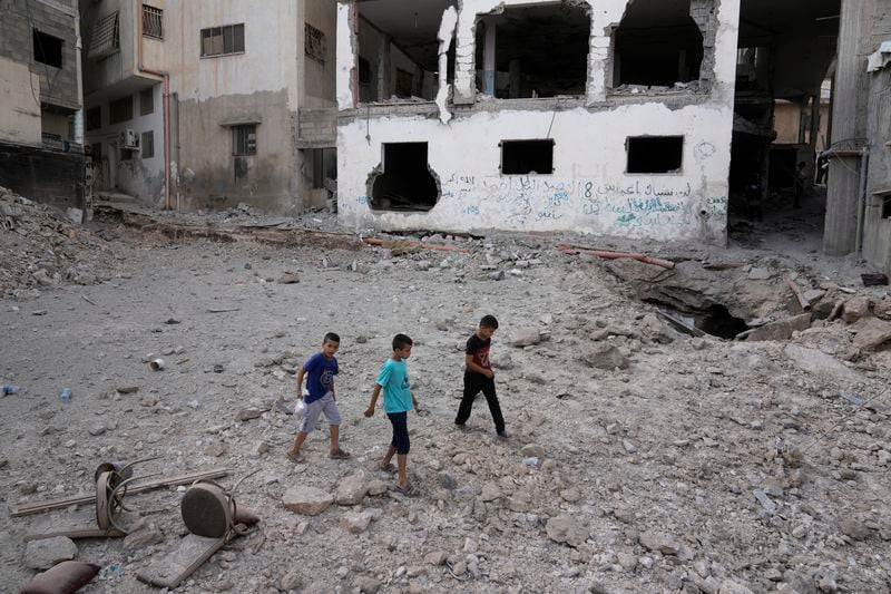 Palestinians walk past a damaged building following an Israeli military operation in the West Bank city of Jenin on Friday, Sept. 6, 2024. (AP Photo/Majdi Mohammed)