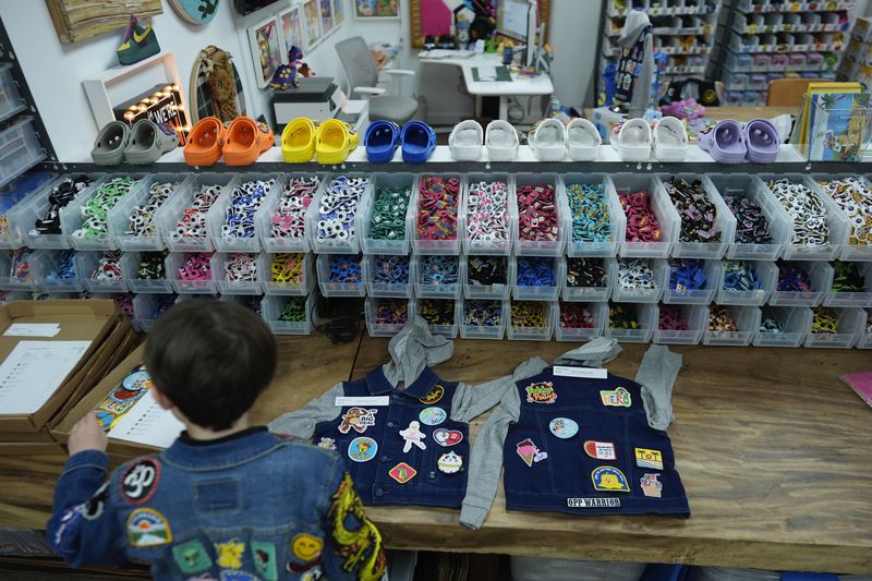 Oliver Burkhardt, 13, shows how staff lays out patches on denim jackets being prepared for kids battling cancer, inside the offices of the Oliver Patch Project, Wednesday, Sept. 4, 2024, in Miami. (AP Photo/Rebecca Blackwell)