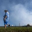 Darryl Shumake walks along Iris Drive at mid-morning Wednesday, Oct 2, 2024 as a large mile-long plume was still visible over Conyers as crews worked at the BioLab plant that caught on fire days earlier. But as the sun lifted above the horizon, so did the shelter-in-place order for Rockdale County residents. Those living nearby have been advised to stay inside every evening through early morning until Friday. (John Spink/AJC)