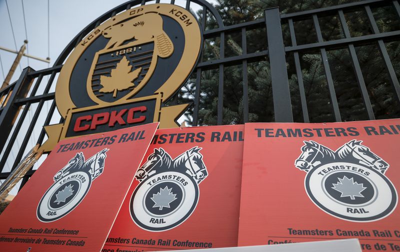 Teamsters Canada Rail Conference picket sign lean up againts a CPKC logo outside the company's headquarters in Calgary, Alta., Friday, Aug. 23, 2024.(Jeff McIntosh /The Canadian Press via AP)