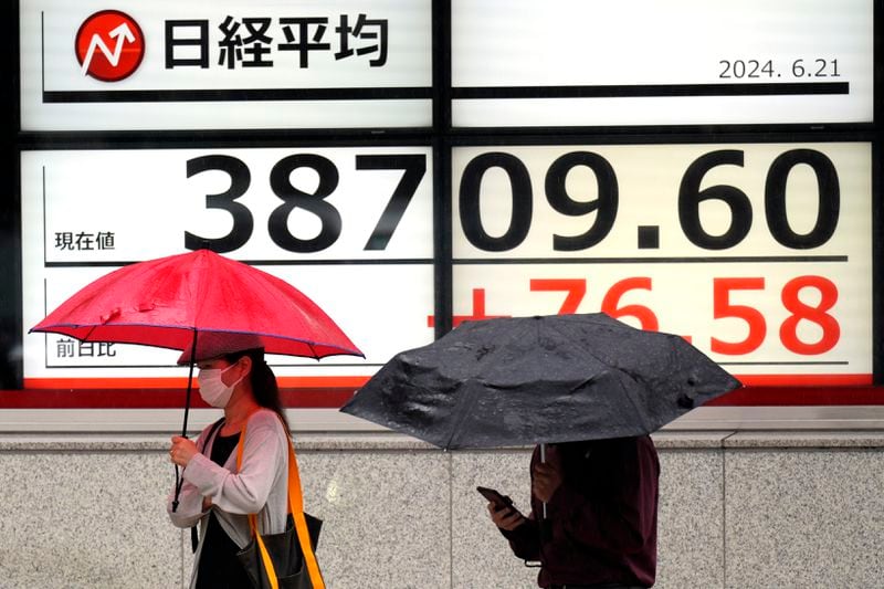 People walk in front of an electronic stock board showing Japan's Nikkei 225 index at a securities firm Friday, June 21, 2024, in Tokyo. (AP Photo/Eugene Hoshiko)