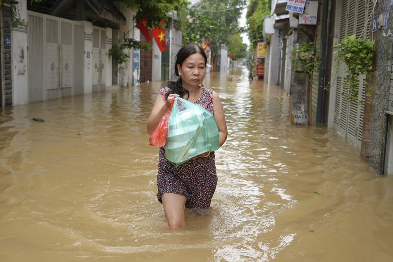 Local resident Nguyen Thi Hoa carries food to her home in a flooded street in the aftermath of Typhoon Yagi, in Hanoi, Vietnam on Thursday, Sept. 12, 2024. (AP Photo/Hau Dinh)