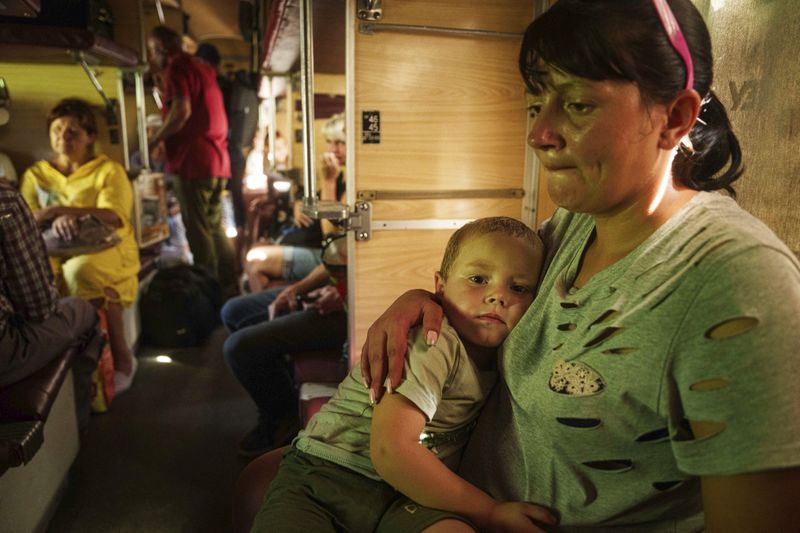 Alla hugs her son Ivan sitting in evacuation train in Pokrovsk, Donetsk region, Ukraine, on Monday, August 19, 2024. Due to the advance of Russian troops to the west towards Myrograd, Alla and her son Ivan were forced to evacuate as volunteers. Intensive shelling forced people to leave homes. (AP Photo/Evgeniy Maloletka)