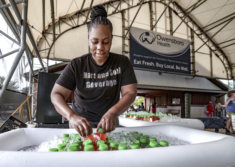 FILE - Crashaunya Hartsfield with Hart and Soul Beverages arranges organic cold-pressed juices, herbal teas, and organic lemonade at the Owensboro Regional Farmers Market in Owensboro, Ky., on Aug. 31, 2024. (Greg Eans/The Messenger-Inquirer via AP, File)