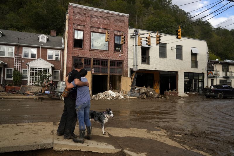 Resident Anne Schneider, right, hugs her friend Eddy Sampson as they survey damage left in the wake of Hurricane Helene, Tuesday, Oct. 1, 2024, in Marshall, N.C. (AP Photo/Jeff Roberson)