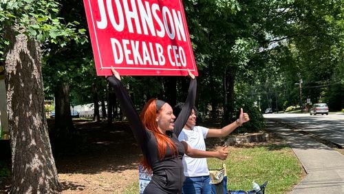 Nylah McDowell and Iona Atwaters, 19-year-old volunteers for DeKalb County CEO candidate Larry Johnson, encourage passing motorists on Lavista Road to cast their ballots in Tuesday's general primary.