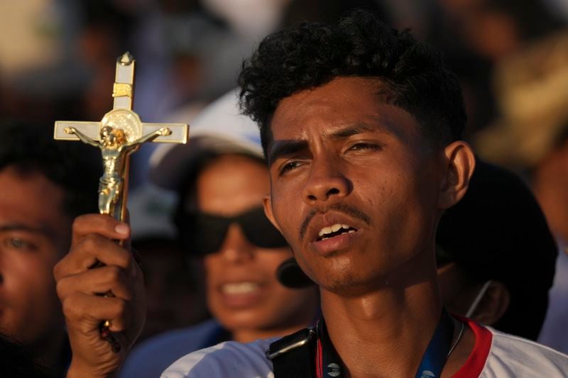 A catholic faithful holds a cross during the holy mass lead by Pope Francis at Tasitolu park in Dili, East Timor, Tuesday, Sept. 10, 2024. (AP Photo/Dita Alangkara, Pool)