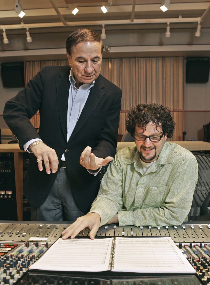 FILE - Composers Richard M. Sherman, left, who, along with his brother Robert, wrote the song "It's a Small World" for the Disneyland ride of the same name, and Michael Giacchino, right, who composed the driving music for Disneyland's newly-redesigned "Space Mountain" ride, work in a sound room at Walt Disney Imagineering offices in Glendale, Calif., July 5, 2005. Sherman, one half of the prolific, award-winning pair of brothers who helped form millions of childhoods by penning classic Disney tunes, died Saturday, May 25, 2024. He was 95. (AP Photo/Kevork Djansezian, File)