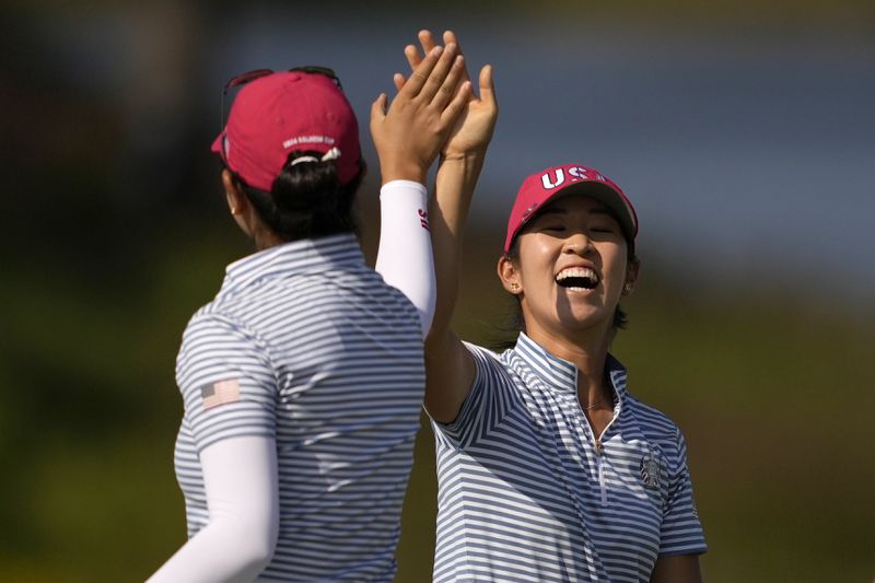 United States' Rose Zhang, right, is congratulated by teammate United States' Andrea Lee after hitting out of a bunker and into the cup on the 13th hole during a Solheim Cup golf tournament fourball match at Robert Trent Jones Golf Club, Saturday, Sept. 14, 2024, in Gainesville, Va. (AP Photo/Matt York)