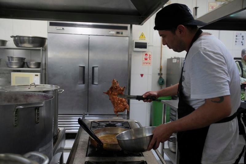 A cook fries guinea pigs at a restaurant in Lima, Peru, Thursday, Oct. 3, 2024. Guinea pigs, locally known as 'cuy,' have been traditionally raised for meat consumption since pre-Inca times. (AP Photo/Guadalupe Pardo)