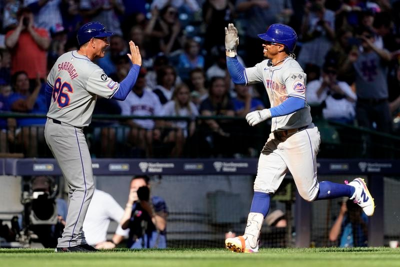 New York Mets' Francisco Lindor, right, is congratulated by third base coach Mike Sarbaugh, left, after hitting a solo home run during the sixth inning of a baseball game against the Milwaukee Brewers, Sunday, Sept. 29, 2024, in Milwaukee. (AP Photo/Aaron Gash)