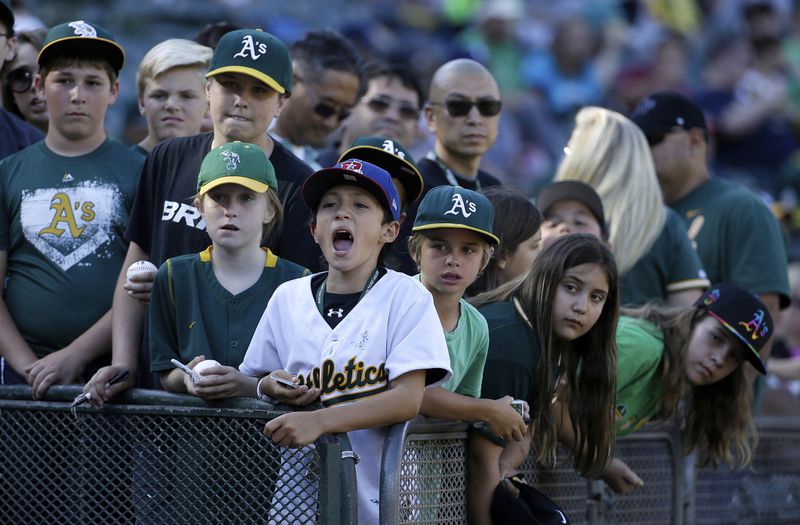 FILE - Fans wait for autographs before a baseball game between the Oakland Athletics and the Seattle Mariners in Oakland, Calif., July 3, 2015. (AP Photo/Jeff Chiu, File)