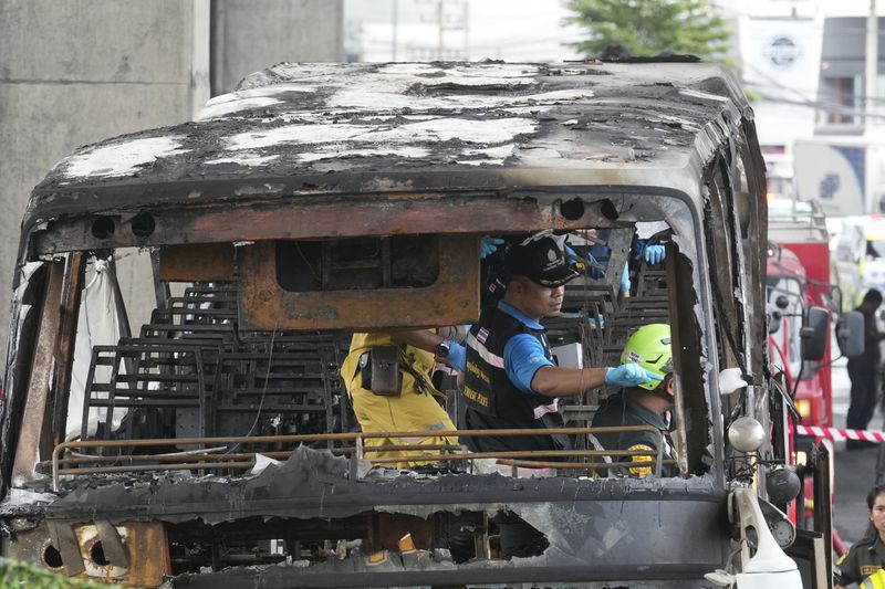 Officers of a police forensics team inspect a bus that caught fire, carrying young students with their teachers, in suburban Bangkok, Tuesday, Oct. 1, 2024. (AP Photo/Sakchai Lalit)