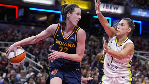 Indiana Fever guard Caitlin Clark (22) makes a behind the back pass in front of Dallas Wings guard Sevgi Uzun (1) in the second half of a WNBA basketball game in Indianapolis, Sunday, Sept. 15, 2024. (AP Photo/Michael Conroy)