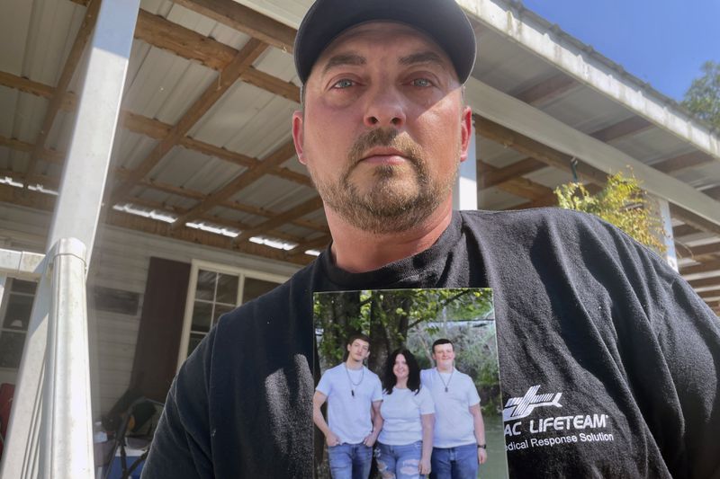 Ryan Craddock holds a photo of his three children, from left, Shawn Craddock, 18; Kendall Craddock, 17, and Cohen Craddock, 13, at his home in Hewett, W. Va., on Thursday, Aug. 29, 2024. Cohen died Saturday, Aug. 24, 2024, a day after he received a head injury while making a tackle during his middle school's football practice. (AP Photo/John Raby)