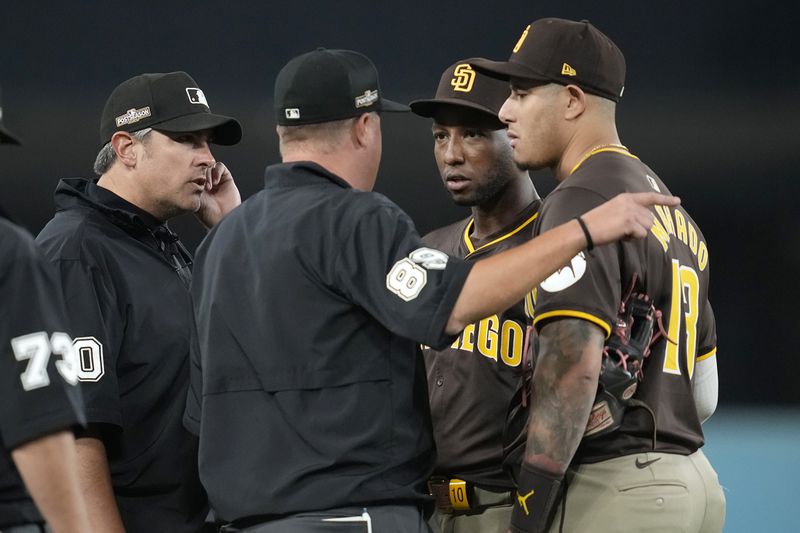 San Diego Padres left fielder Jurickson Profar, second from right, and third baseman Manny Machado talk to the umpires after items were thrown at Profar in the outfield during the seventh inning in Game 2 of a baseball NL Division Series against the Los Angeles Dodgers, Sunday, Oct. 6, 2024, in Los Angeles. (AP Photo/Ashley Landis)