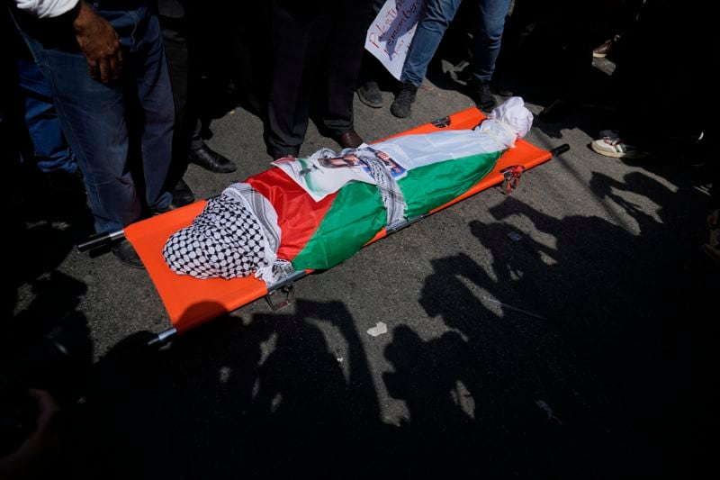 Mourners pray over the body of Aysenur Ezgi Eygi, 26, who was fatally shot by Israeli soldiers while participating in an anti-settlement protest in the West Bank, during her funeral procession in the West Bank city of Nablus, Monday, Sept. 9, 2024. (AP Photo/Nasser Nasser)