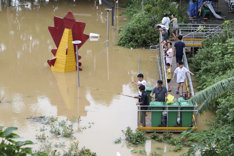 People fish next to a submerged playground due to flood , following Typhoon Yagi in Hanoi, Vietnam on Tuesday, Sept. 10, 2024. (AP Photo/Huy Han)