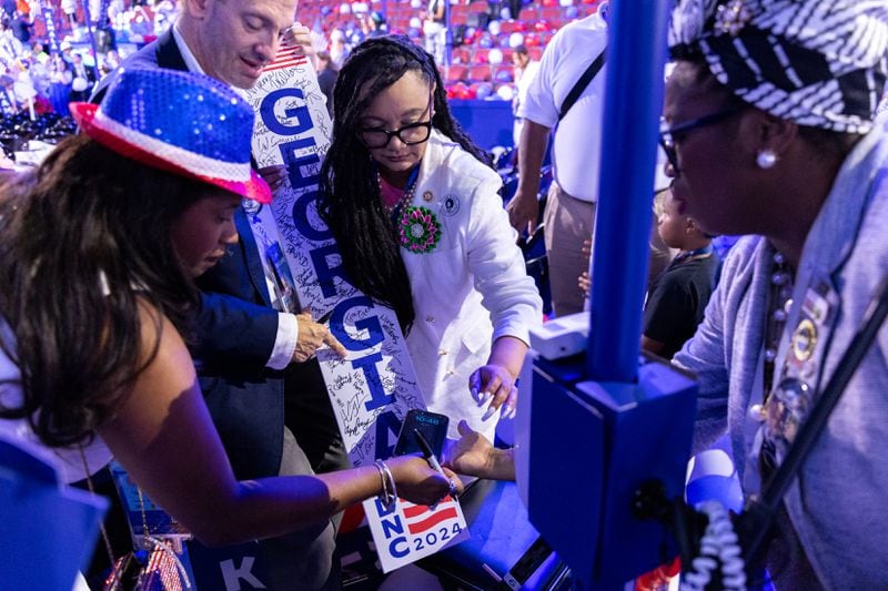 The Georgia delegation, including U.S. Rep. Nikema Williams of Atlanta (center), sign the state delegation marker on the final day of the Democratic National Convention in Chicago.