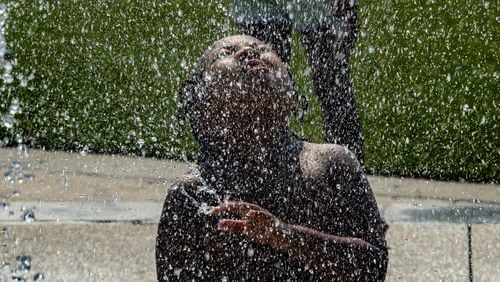 Devonte Tucker Jr.-6, a kindergartener with Wesley International Academy enjoyed the spray of cool water at the splash pad at Rodney Cook Sr. Park in Historic Vine City. (John Spink/AJC File Photo)