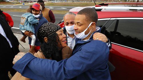 Devonia Inman is embraced by his mother, Dinah Ray, and stepfather, David Ray, after being released from custody Dec. 20, 2021, from the Augusta State Medical Prison (background) after serving 23 years for a wrongful conviction. His charges were dismissed in a murder case. Legislation has been proposed to give Inman more than $1.6 million as compensation for the time he was incarcerated. Curtis Compton / Curtis.Compton@ajc.com