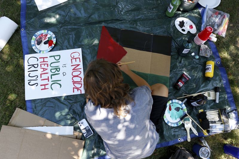 A woman paints a Palestinian flag on Sunday, Aug. 11, 2024, at a park on Chicago's South Side, for March on DNC events in which protesters planned to pressure Democratic nominee Kamala Harris and others in her party to end aid to Israel and broker a cease-fire. (AP Photo/Martha Irvine)