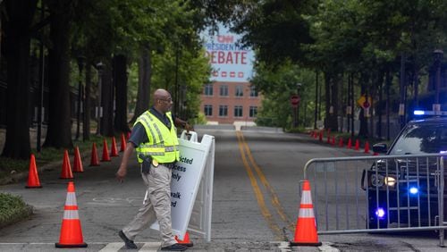 Captain A. Hill with the Georgia Tech Police moves signage into place along Fowler Street and 6th Street as roads closed early Thursday morning, June 27, 2024 near CNN Studios on the Techwood campus in Midtown ahead of Thursday night’s debate between President Joe Biden and former President Donald Trump. (John Spink/AJC)