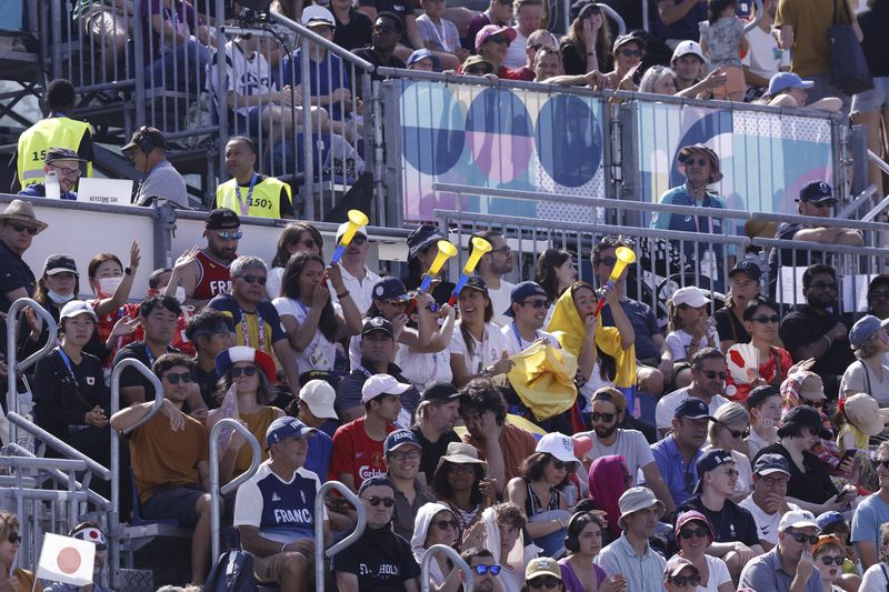 Event attendees cheer and make noise using vuvuzelas during the men's blind football preliminary match between Japan and Colombia during the Paralympic Games in Paris on Sunday, Sept. 1, 2024. Football fans are known for being loud and rowdy. But the Paralympic sports most closely related to football, blind football and goalball, require spectators to be silent during game action so that players can receive audible cues from the ball and the environment. (AP Photo/Felix Scheyer)