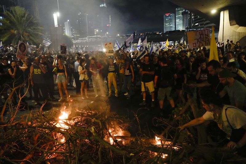 People block a road as they protest calling for a deal for immediate release of hostages held in the Gaza Strip by the Hamas militant group, in Tel Aviv, Sunday, Sept. 1, 2024. (AP Photo/Ariel Schalit)