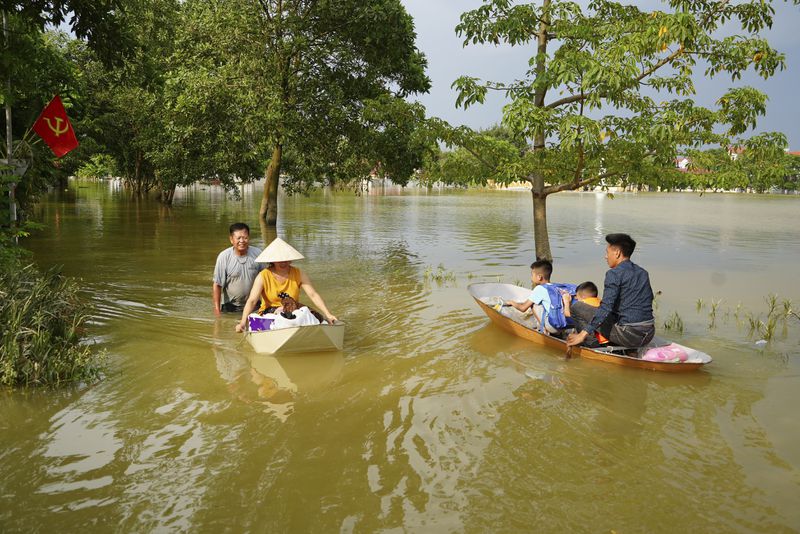 People sit on a boat to get to their flooded homes in the aftermath of Typhoon Yagi in An Lac village, Hanoi, Vietnam Friday, Sept. 13, 2024. (AP Photo/Hau Dinh)