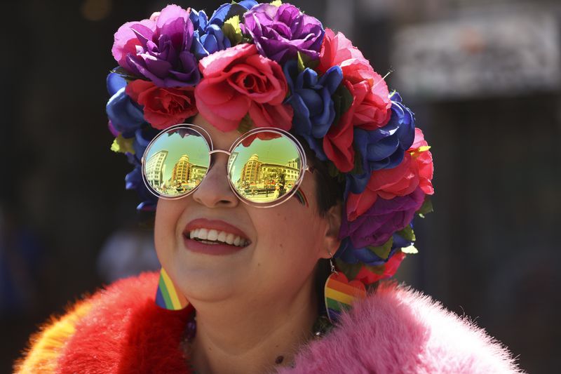 A reveler smiles as buildings are reflected in their face during a Pride Parade, Sunday, June 30, 2024, in San Francisco. (AP Photo/Ethan Swope)