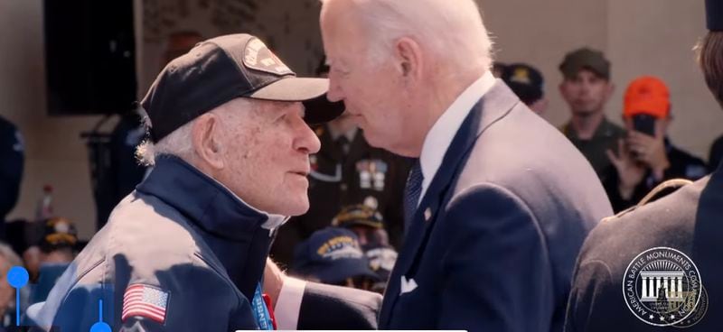 President Joe Biden prepares to kiss the cheek of World War II veteran Hilbert Margo during a ceremony in Normandy.